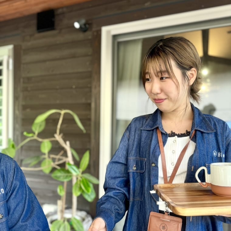 川越理子さんが笑顔でカフェトレイを持っている様子